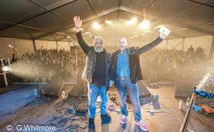 Mick Peat and Bob Rushton waving happily from the stage of a packed tent at Derby Folk Festival