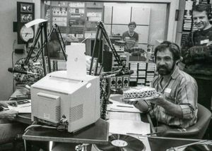 A vintage photo of Mick Peat at Radio Derby, holding a birthday cake