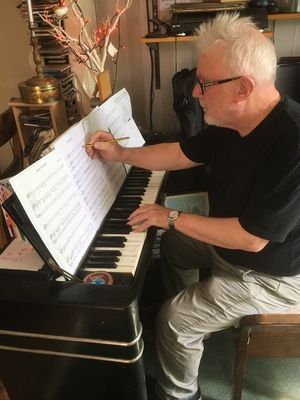 Pete sitting at the piano making notations on sheet music